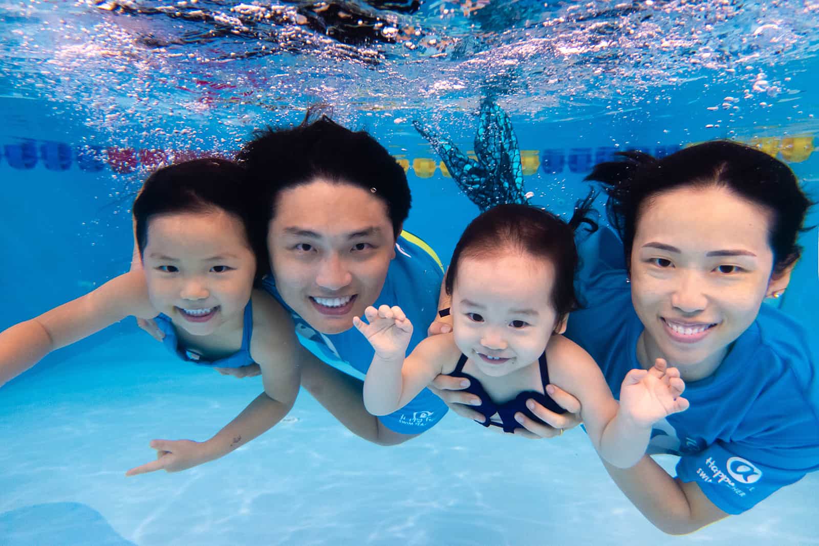 Happy Fish swim school instructors with two young learners underwater